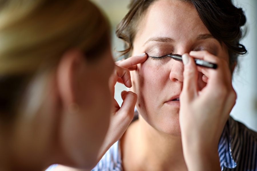 A bride getting fake lashes on her wedding day.